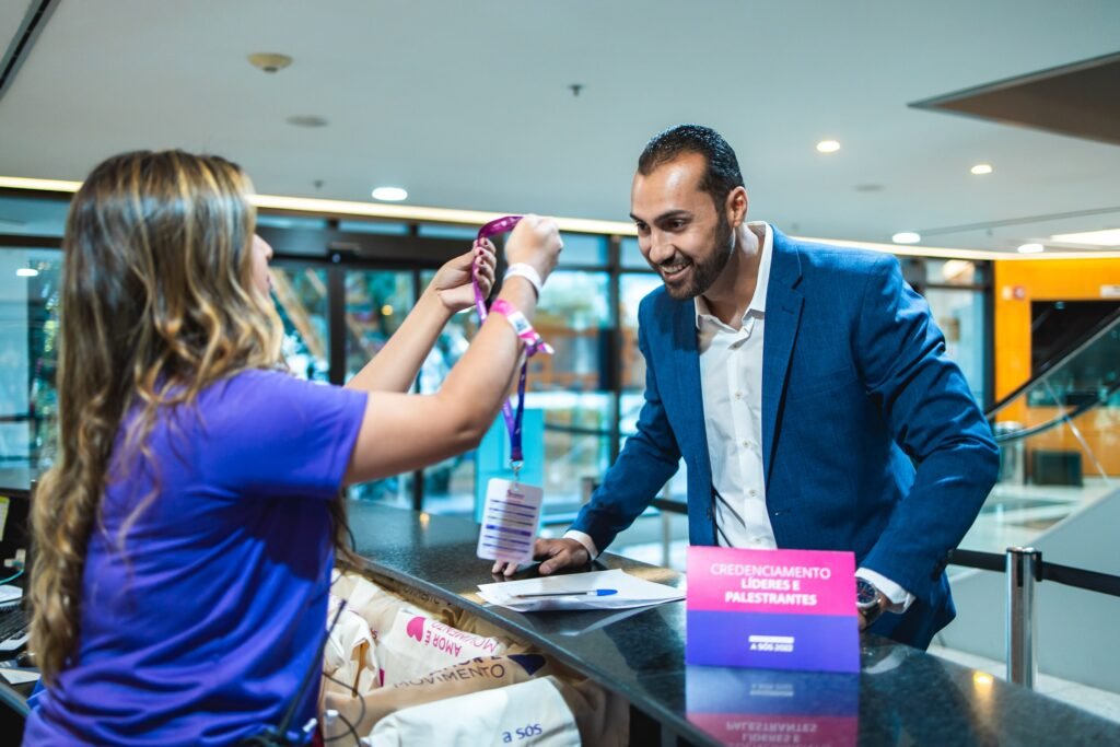 Foto de uma pessoa recebendo o crachá no check-in de um evento. 